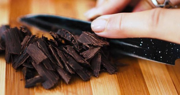 Photo of a woman who is cutting chocolate curls with a knife - Photo, Image