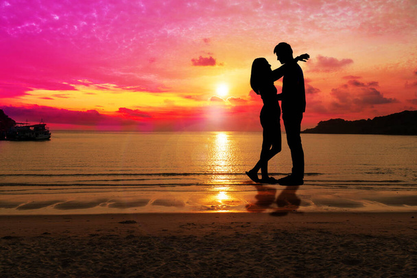 シルエットの幸せな若いカップルは、コピースペースのある熱帯ビーチで日没でお互いを受け入れています。人々は美しい空とビーチに立っている。コンセプト愛とバレンタインデー. - 写真・画像