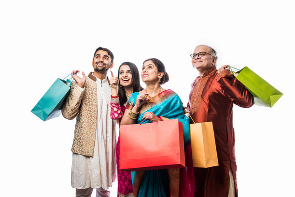 Fröhliche indische Familieneinkäufe für das Diwali-Fest oder die Hochzeit, mit bunten Papiertüten, isoliert auf weiß - Foto, Bild