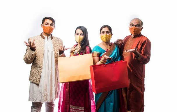 Fröhliche indische Familieneinkäufe zum Diwali-Fest oder zur Hochzeit mit Schutzmaske, isoliert auf weiß - Foto, Bild