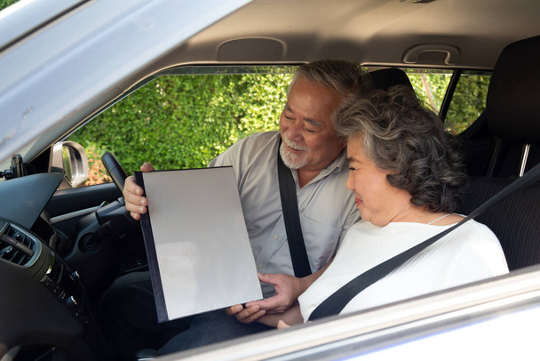 szczęśliwy Azji senior para siedzi w samochód i gospodarstwa ubezpieczenie dokument - Zdjęcie, obraz