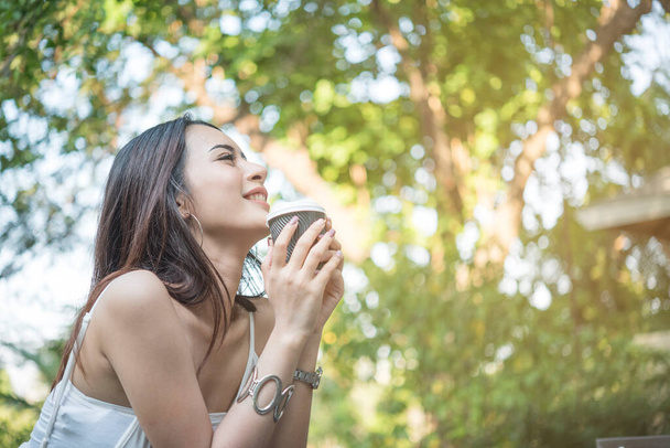 Jovem bela mulher sentindo-se feliz e poderoso enquanto bebe café no parque pela manhã - Foto, Imagem