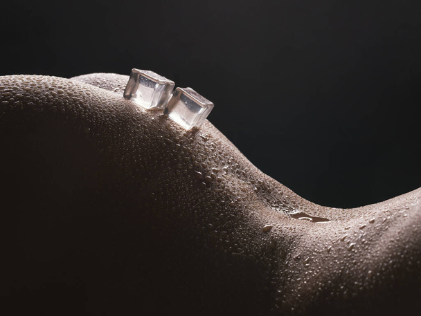 Ice cubes lying on woman body cropped shot - Foto, afbeelding