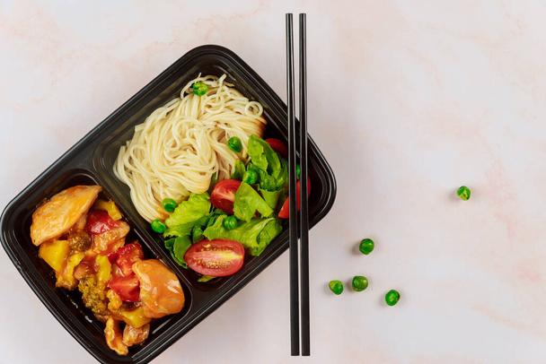 Chinesisches Essen im Plastikbehälter mit Essstäbchen. Konzept der Essensausgabe. - Foto, Bild