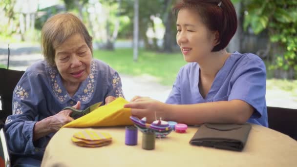 Пожилая женщина с сиделкой в игольнице ремесел профессиональная терапия от болезни Альцгеймера или слабоумия - Кадры, видео