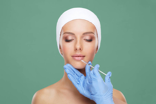 Doctor injecting in a beautiful face of a young woman. Plastic surgery, skin lifting and aesthetic medicine concept. - Фото, изображение
