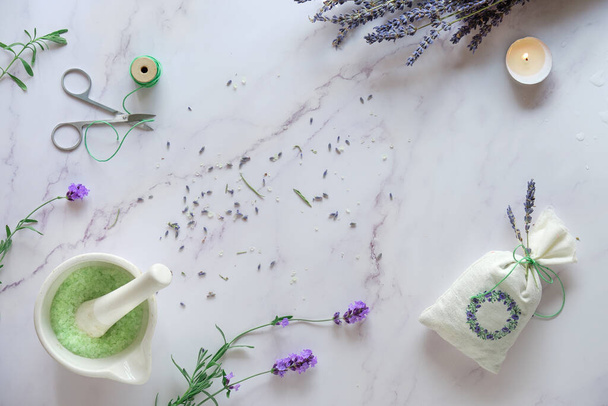 Handmade lavender sachets and home made sugar scrub. Fresh and dry lavender flowers. Flat lay on white marble with candle. - Foto, immagini