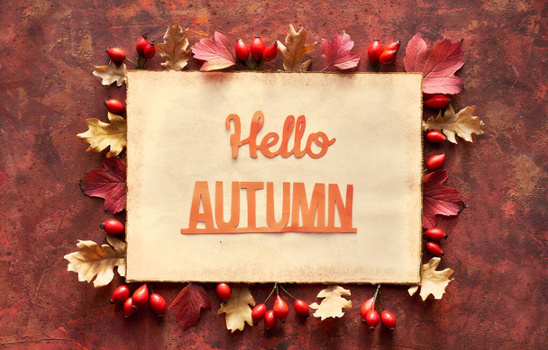 Paper craft, text Hallo Autumn on aged paper page. Dark red and brown Fall frame with decorative border from oak Autumn leaves. - Foto, immagini