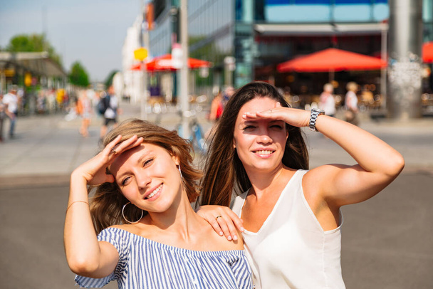 Two girlfriends cover their face from the sun with their hands - Φωτογραφία, εικόνα