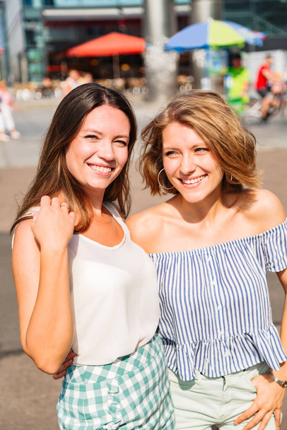 Blonde woman hugs her friend and smiles at camera - Foto, immagini