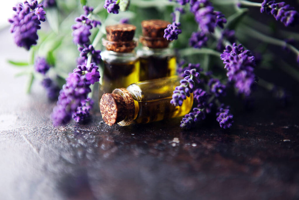 levandulový olej ve skleněné láhvi na pozadí čerstvých květin na stole - Fotografie, Obrázek