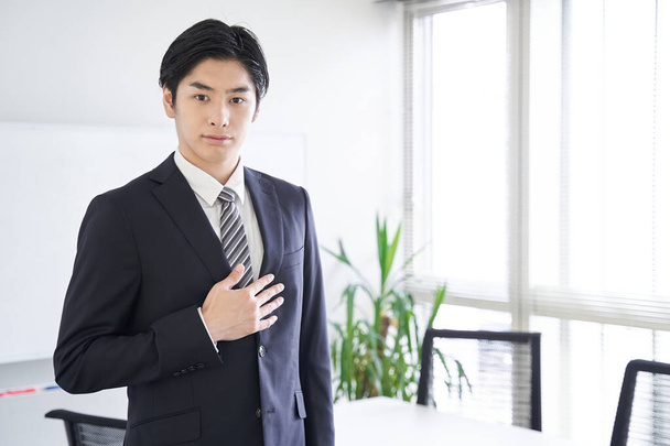 Ein japanischer Geschäftsmann legt sich in einem Konferenzraum die Hand auf die Brust - Foto, Bild