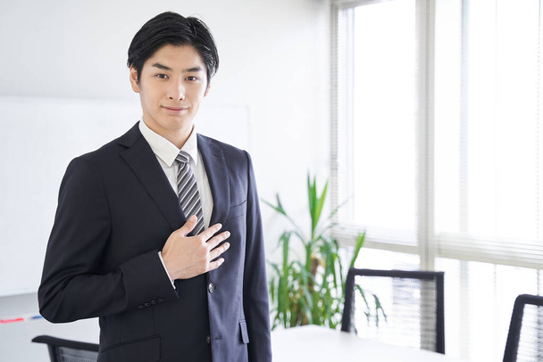 Ein japanischer Geschäftsmann legt sich in einem Konferenzraum die Hand auf die Brust - Foto, Bild