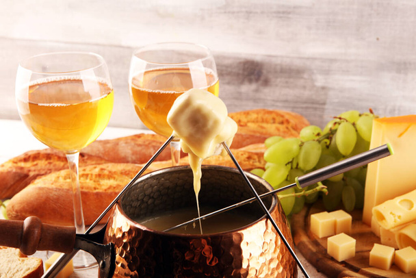 Bir kış akşamı gurme İsviçre fondü yemeği tahtanın üzerinde çeşitli peynirlerle birlikte çatallı ve peynirli fondü.  - Fotoğraf, Görsel