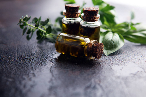 Свежие сырые травы из сада и различные масла для массажа и ароматерапии на столе - Фото, изображение
