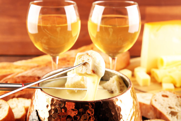 Bir kış akşamı gurme İsviçre fondü yemeği tahtanın üzerinde çeşitli peynirlerle birlikte çatallı ve peynirli fondü.  - Fotoğraf, Görsel