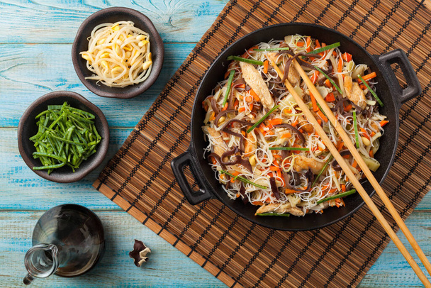 Rice noodles with chicken, mushrooms mun and vegetables, prepared in wook. Top view. - Foto, afbeelding