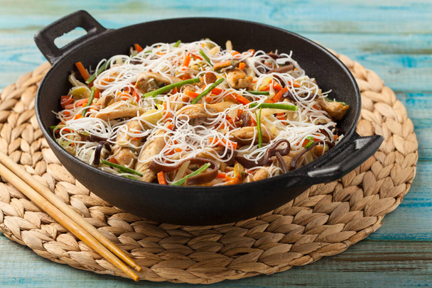 Makaron ryżowy z kurczakiem, grzybami i warzywami, przygotowany w wooku.  - Zdjęcie, obraz