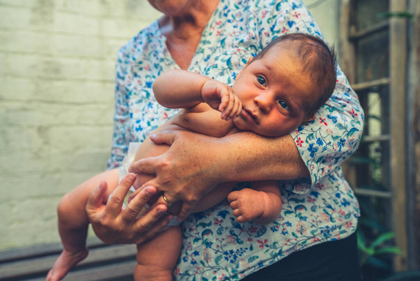 Bir büyükanne bebeğini kucağında tutuyor. - Fotoğraf, Görsel