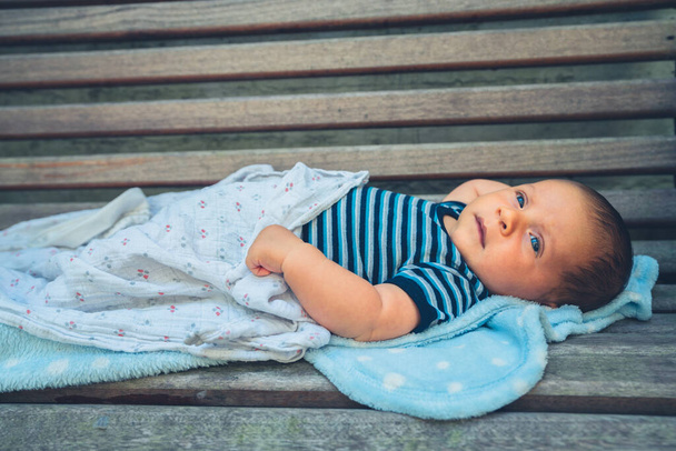 A little baby is resting on a bench - Foto, Bild