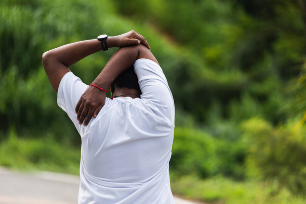 Close up Asian young sport runner black man athlete warming up doing stretch arms before running at the outdoor street health park, healthy exercise injury from workout concept - Photo, image