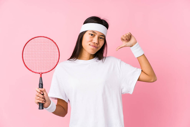 Giovane donna cinese che gioca badminton in uno sfondo rosa si sente orgoglioso e sicuro di sé, esempio da seguire. - Foto, immagini