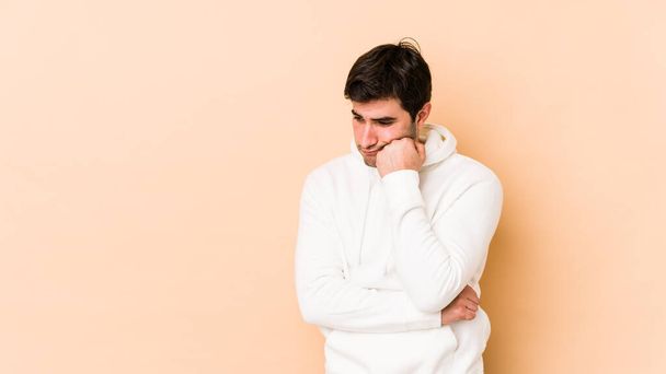 Young man isolated on beige background who feels sad and pensive, looking at copy space. - Photo, image