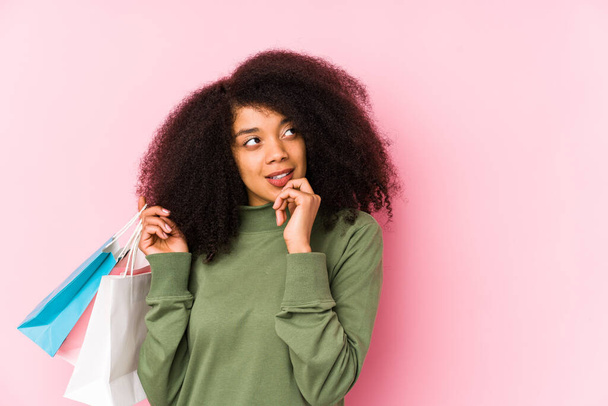 Young afro woman shopping isolated Young afro woman buying isolaYoung afro woman holding a roses isolated relaxed thinking about something looking at a copy space - Photo, image