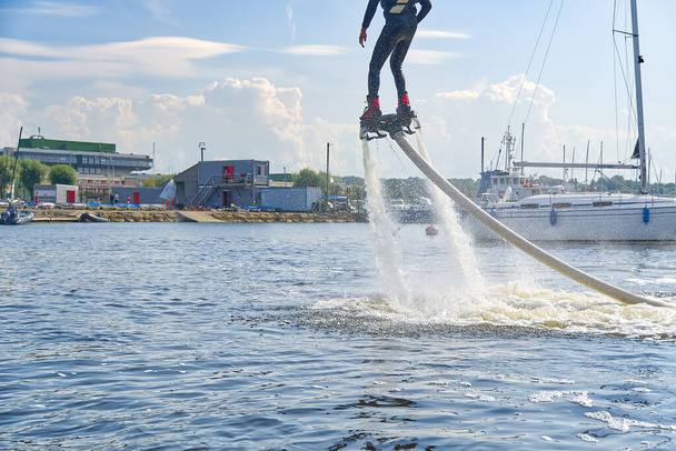 muž se baví na Flyboardu. Flyboarding za slunečného letního dne u řeky v přístavu. Extrime water activity flyboard. - Fotografie, Obrázek