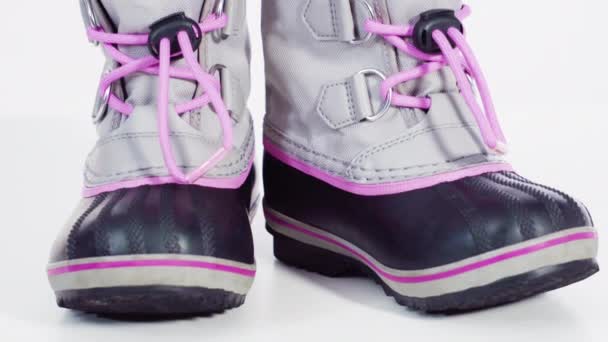 Niña rosa y gris botas de invierno cálidas e impermeables sobre un fondo blanco. - Metraje, vídeo