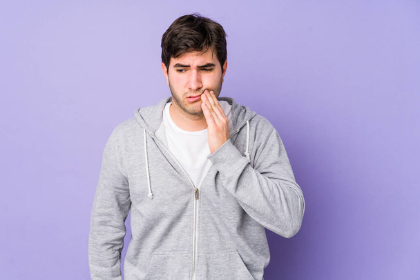 Junger Mann isoliert auf violettem Hintergrund mit starken Zahnschmerzen, Backenschmerzen. - Foto, Bild