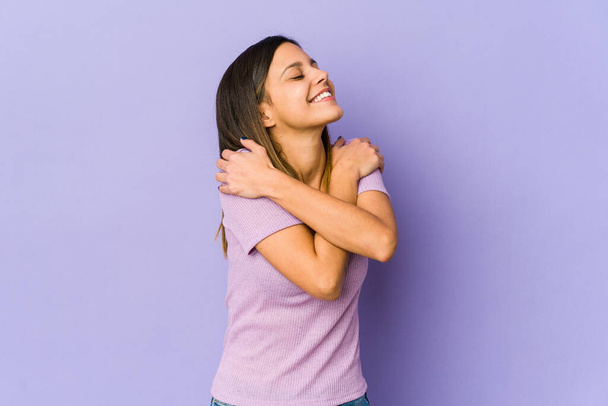 Young woman isolated on purple background hugs, smiling carefree and happy. - Fotó, kép