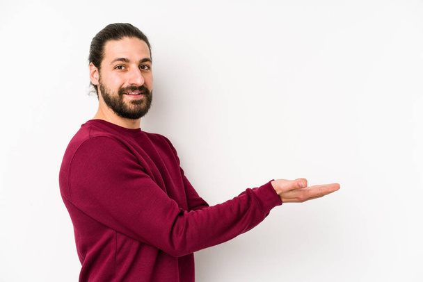 Young long hair man isolated on a white background holding a copy space on a palm. - Foto, immagini