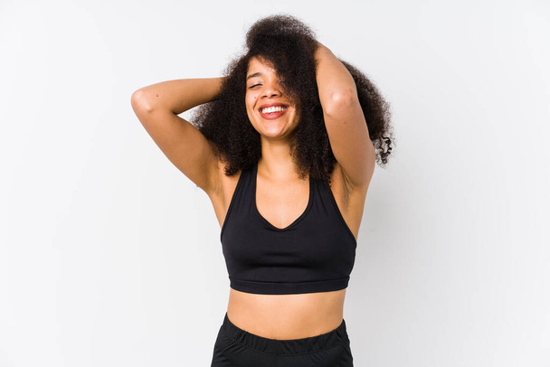 Young african american sporty woman laughs joyfully keeping hands on head. Happiness concept. - Photo, Image