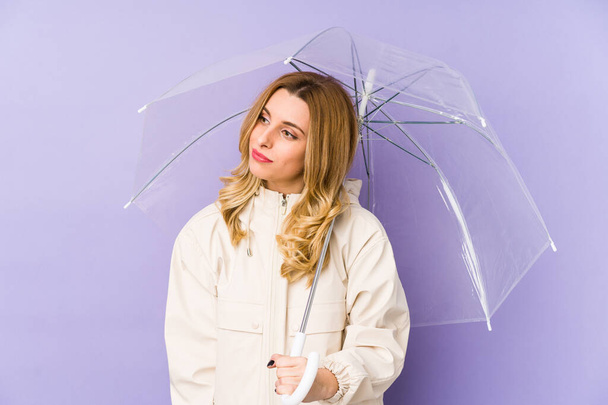 Mujer rubia joven sosteniendo un paraguas aislado Mujer rubia joven sosteniendo un paraguas aislado soñando con lograr objetivos y propósitos - Foto, Imagen