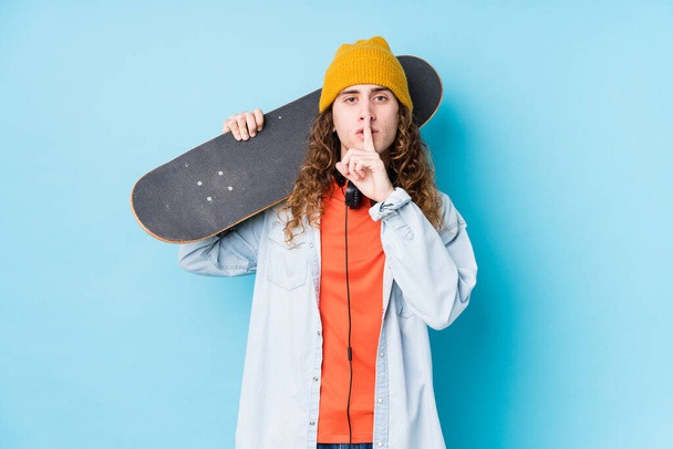 Young caucasian skater man isolated keeping a secret or asking for silence. - Foto, imagen