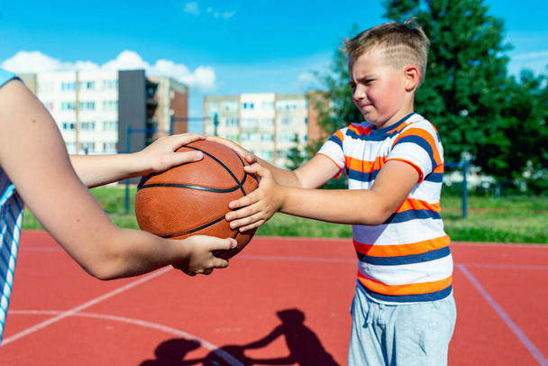 Atrakcyjne kaukaskie dwa małe koszykarze trzyma piłkę na zewnątrz czerwony jasny sąd - Zdjęcie, obraz
