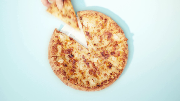 Widok człowieka biorącego kawałek pizzy na niebieskim tle - Materiał filmowy, wideo