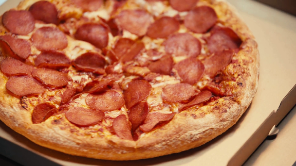 Draaiende pizza met salami op kartonnen dozen op grijze achtergrond - Video
