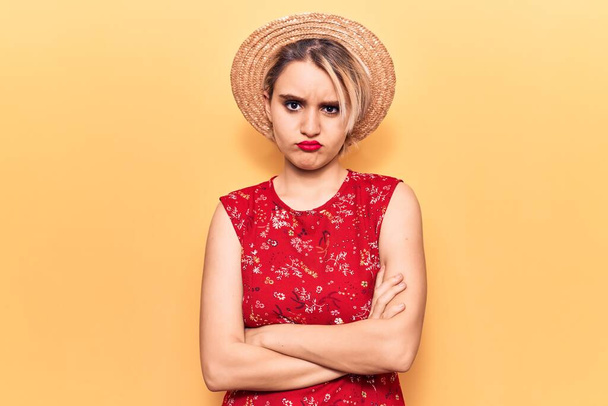 Young beautiful blonde woman wearing summer hat skeptic and nervous, disapproving expression on face with crossed arms. negative person.  - Photo, Image