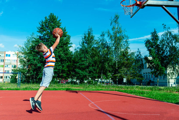 Telsiai, Litvánia 08 12 2020 Vonzó kaukázusi kis kosárlabda játékos tréning a szabadban piros pálya - Fotó, kép