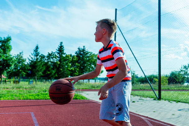 Telsiai, Lituania 08 12 2020 Atractivo pequeño jugador de baloncesto caucásico entrenando en una cancha roja al aire libre - Foto, Imagen