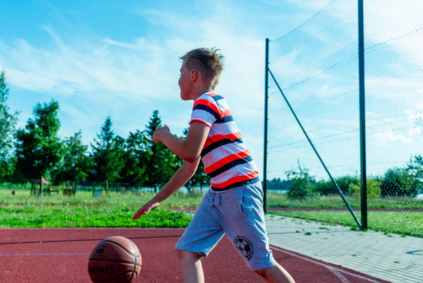 Telsiai, Liettua 08 12 2020 Houkutteleva valkoihoinen pikku koripalloilija treenaa ulkona punaisella kentällä - Valokuva, kuva