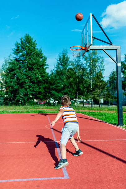 Telsiai,Lithuania 08 12 2020 Attractive caucasian little basketball player training on a outdoors red court - 写真・画像