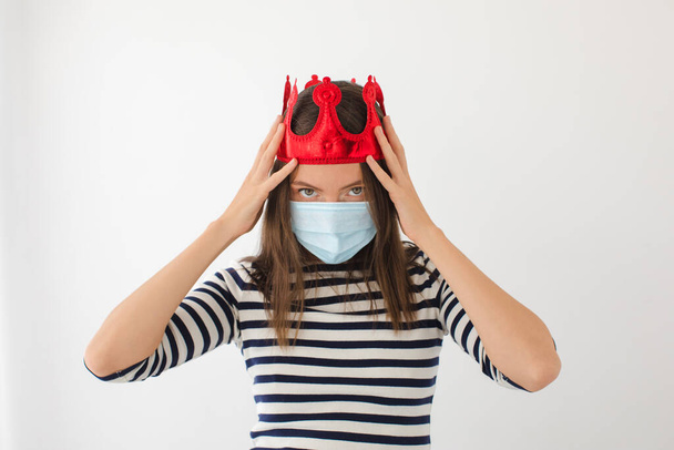 Tıbbi maske ve taç takan genç bir kadın. - Fotoğraf, Görsel