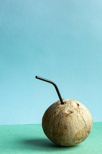 Coconut with a straw on a green-blue background with place for text. Healthy food concept. - Photo, Image
