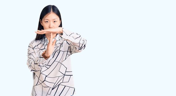 Mladý krásný číňan žena na sobě ležérní tričko odpykávající si čas gesto s rukama, frustrovaný a vážný obličej  - Fotografie, Obrázek