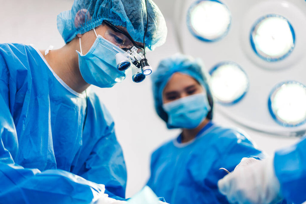 Profesyonel anestezi uzmanı doktor tıp ekibi ve asistanı modern hastane acil servisinde cerrahi ekipmanla jinekolojik ameliyata hazırlanıyor. - Fotoğraf, Görsel