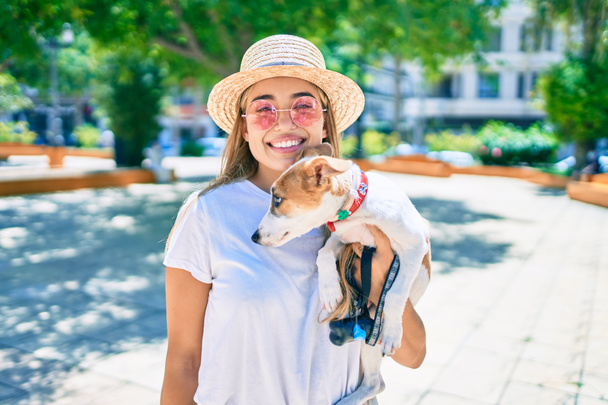 Joven hermosa mujer rubia abrazo y abrazo cachorro perro al aire libre - Foto, imagen