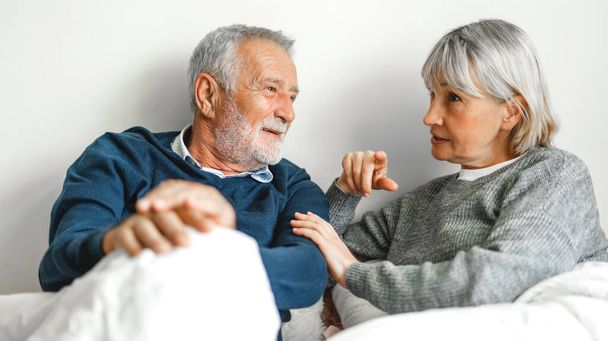 Senior happy couple relaxing and talking together lying on bed in bedroom at home.Retirement couple concept - Photo, Image